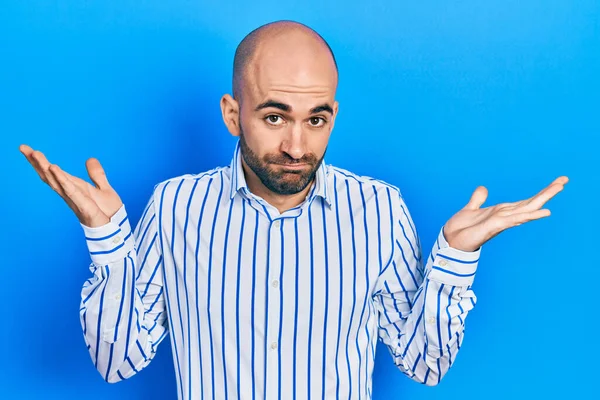 Zarif kıyafetler giyen genç kel adam habersiz ve kolları açık, hiçbir fikri ve şüpheli bir yüzü var.. 