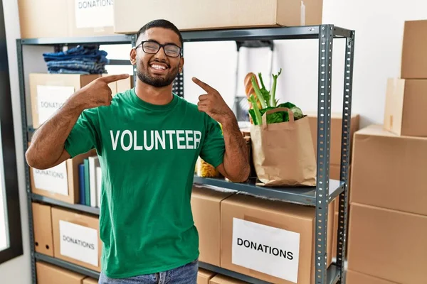 Genç Hintli gönüllü bağış kutusunu tutuyor neşeli bir şekilde gülümsüyor ve parmaklarıyla ve ağzıyla işaret ediyor. diş sağlığı kavramı. 