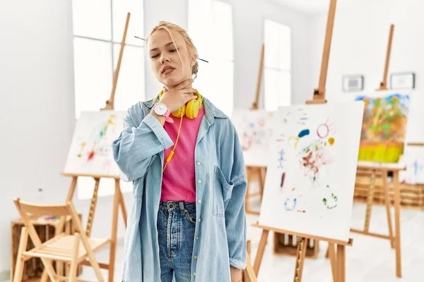 Young caucasian girl at art studio touching painful neck, sore throat for flu, clod and infection