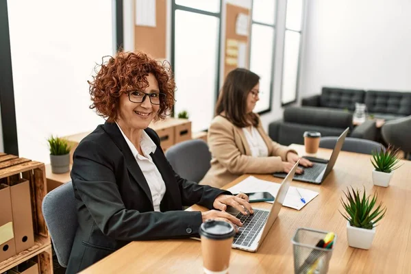 Ofiste çalışan iki kadın grubu. Olgun kadın ve Down sendromlu kız kapsayıcı takım çalışması yapıyor..