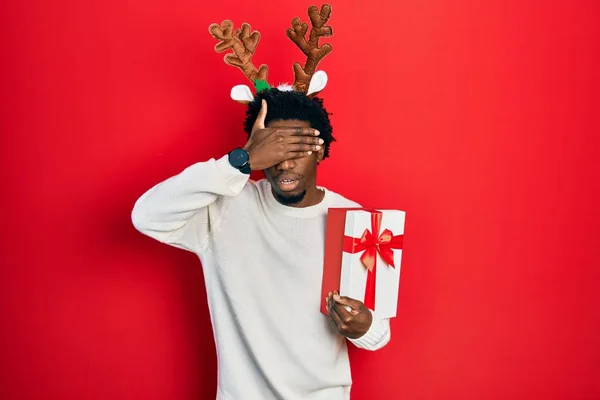 Jovem Afro Americano Vestindo Chapéu Natal Veado Segurando Presente Cobrindo — Fotografia de Stock