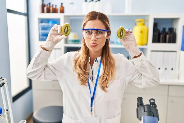 研究室で食べ物を扱う若いブロンドの科学者の女性は落ち込んでおり 苦痛を心配し 怒って恐れています 悲しい表情 — ストック写真