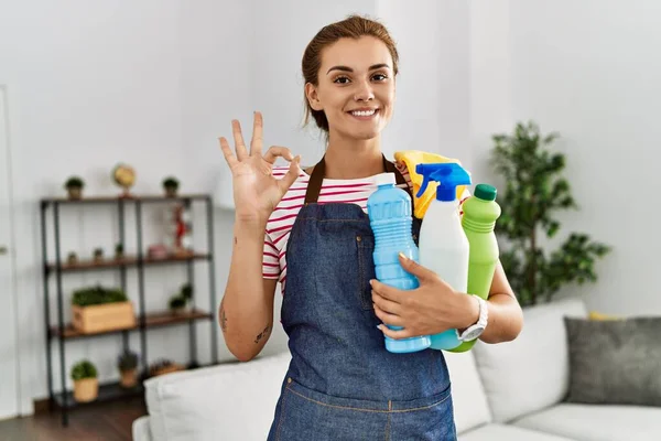 Young Brunette Woman Wearing Apron Holding Cleaning Products Doing Sign — Stock Photo, Image