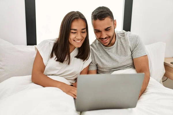 Młoda Latynoska Para Uśmiechnięta Szczęśliwa Korzystając Laptopa Sypialni — Zdjęcie stockowe
