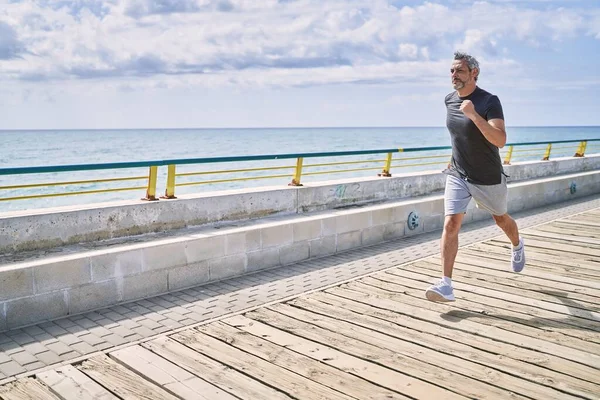 穿着运动服在海滨跑步的中年人 — 图库照片