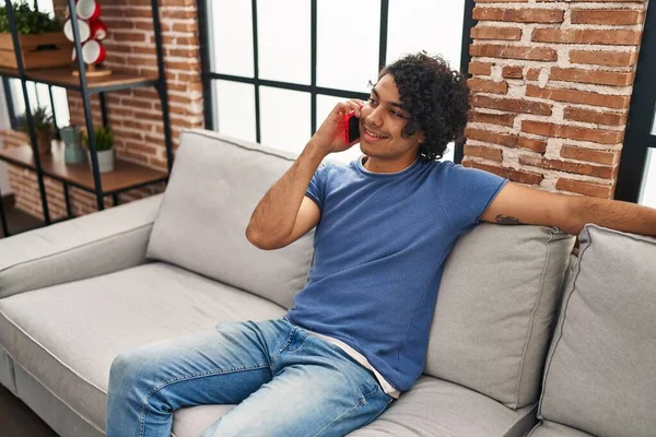 Young Hispanic Man Talking Smartphone Sitting Sofa Home —  Fotos de Stock