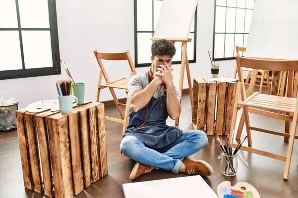 Young Hispanic Man Sitting Art Studio Smelling Something Stinky Disgusting — 图库照片
