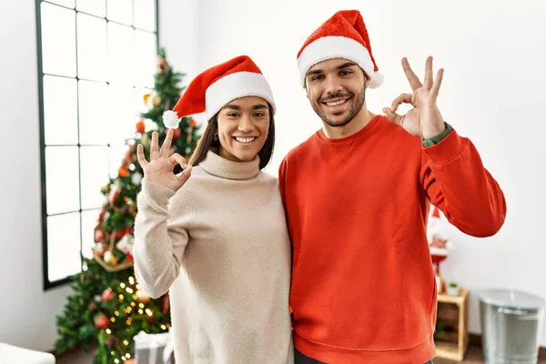 Genç Spanyol Çift Noel Ağacının Yanında Durup Gülümsüyor Parmaklarıyla Tamam — Stok fotoğraf