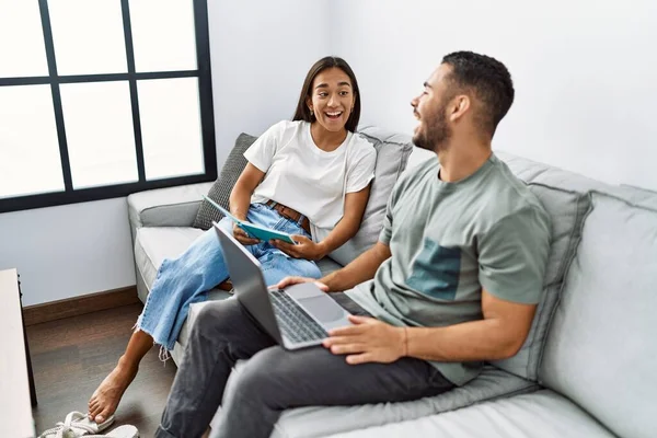 Jovem Casal Latino Usando Laptop Livro Leitura Casa — Fotografia de Stock