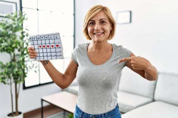 Blonde Frau Mittleren Alters Mit Herzkalender Zeigt Mit Dem Finger — Stockfoto