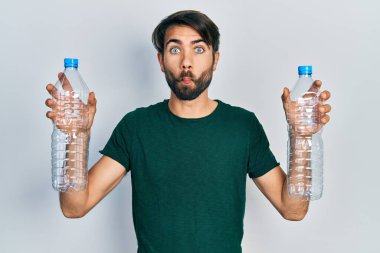 Genç İspanyol adam elinde plastik şişelerle balık suratlı ve şaşı bakışlı çılgın ve komik bakışlar atıyor.. 