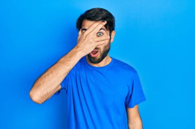 Gündelik kıyafetler giyen genç İspanyol adam şok içinde yüzünü ve gözlerini kapayarak utanmış ifadesiyle parmaklarından bakıyor.. 