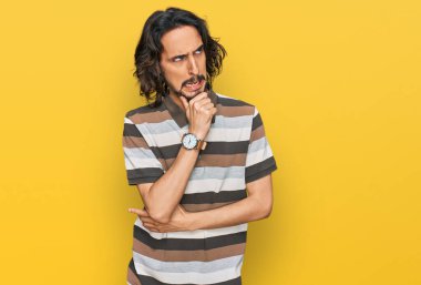 Günlük kıyafetler giyen genç İspanyol bir adam bir soru hakkında endişeli ve gergin bir şekilde düşünüyor. 