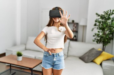 Evde video oyunu oynayan sevimli bir kız VR gözlük kullanıyor.