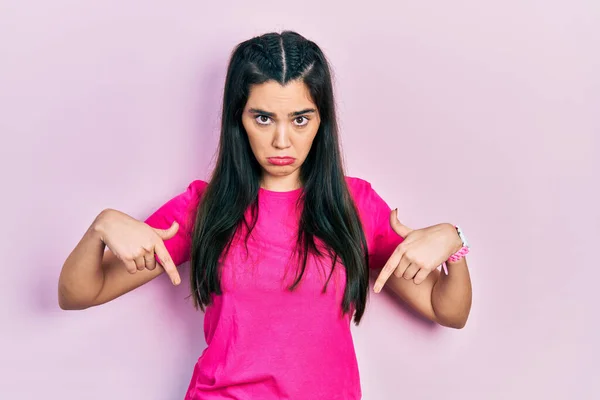 Young Hispanic Girl Wearing Casual Pink Shirt Pointing Looking Sad — стоковое фото