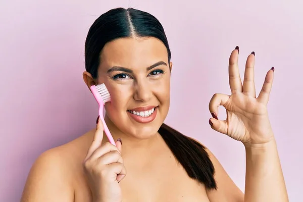 Beautiful Brunette Woman Using Facial Exfoliating Brush Doing Sign Fingers — 스톡 사진