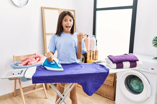 Joven Chica Hispana Planchando Ropa Lavandería Apuntando Con Pulgar Hacia —  Fotos de Stock