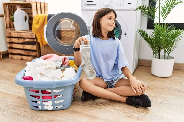 Young Hispanic Girl Doing Laundry Holding Socks Looking Away Side — 스톡 사진