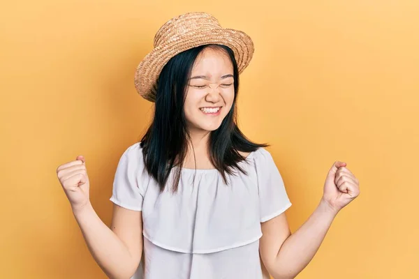 年轻的中国姑娘戴着夏帽 非常高兴 兴奋地举起双臂 做着获胜的手势 微笑着 尖叫着要成功 庆祝概念 — 图库照片