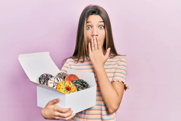 Young Brunette Girl Holding Tasty Colorful Doughnuts Covering Mouth Hand — ストック写真