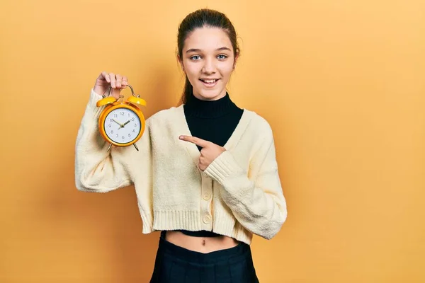 Young Brunette Girl Holding Alarm Clock Smiling Happy Pointing Hand — Stock Photo, Image