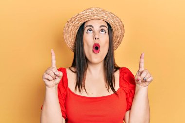 Yaz şapkası takan genç İspanyol kadın şaşırdı ve şaşırdı. Yukarı baktı ve parmaklarıyla işaret etti ve kollarını kaldırdı.. 