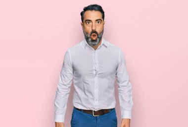 Orta yaşlı, sakallı, sıradan beyaz gömlekli, ağzı açık, korkmuş ve şaşırmış bir adam. 