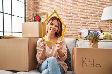 Yeni evdeki kanepede oturan beyaz bir kadın komik bir ifadeyle dilini dışarı çıkartıyor.. 