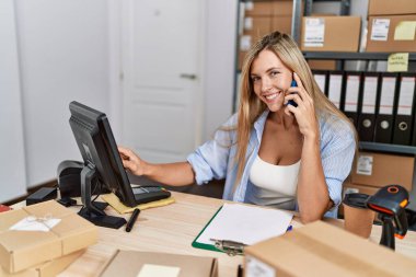 Genç sarışın kadın iş kadını ofisteki akıllı telefondan konuşuyor.