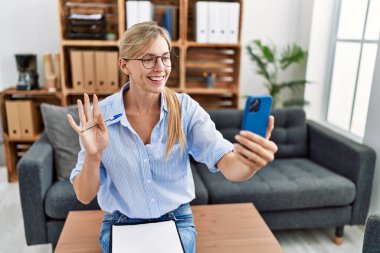 Muayenehanede online terapi seansı yapan güzel bir kadın pozitif ve mutlu görünüyor ve kendine güvenen bir gülümsemeyle dişlerini gösteriyor 