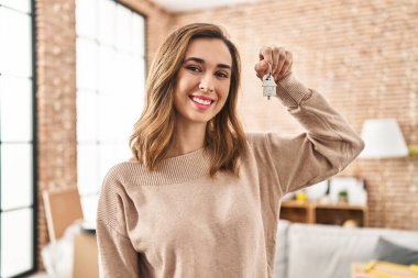 Yeni evin anahtarını elinde tutan kendine güvenen genç bir kadın.