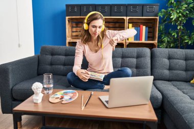 Genç, güzel bir kadın resim pratiği yapıyor. Kızgın yüzüyle özel derse bakıyor. Negatif işaretler baş parmakları aşağıda, reddedilme konsepti reddediyor. 