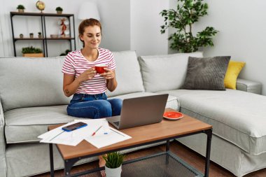 Kahve içen genç bir kadın evde çalışıyor.