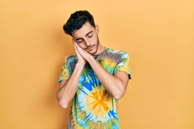 Gündelik kıyafetler giyen genç İspanyol adam uyur. Yorgun düşler kurar, ellerle poz verir, gözleri kapalı gülümserdi.. 