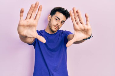 Gündelik tişört giyen, elleri ve parmakları kullanarak çerçeve yapan Latin asıllı genç bir adam. 