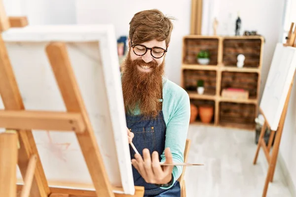 年轻的红头发男人在画室里自信地微笑着画画 — 图库照片