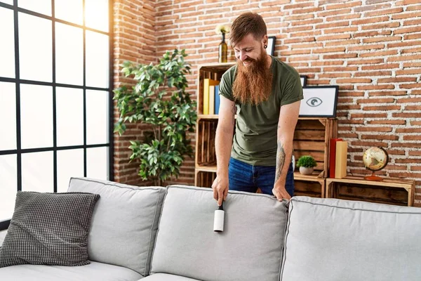 Young Redhead Man Cleaning Sofa Using Pet Hair Roller Home — ストック写真