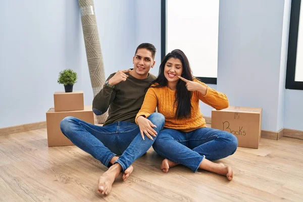 Young Couple Sitting Floor New Home Smiling Cheerful Showing Pointing — Zdjęcie stockowe