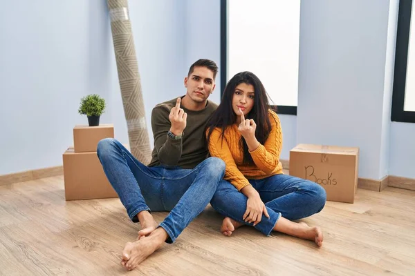 Young Couple Sitting Floor New Home Showing Middle Finger Impolite — 스톡 사진