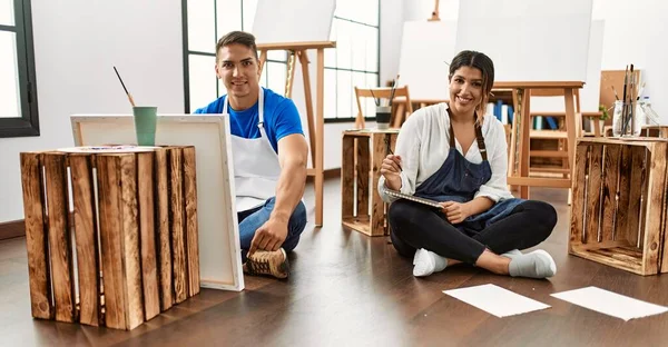 Sanat stüdyosundaki genç İspanyol çift pozitif ve mutlu görünüyorlar. Durup gülümsüyorlar ve dişlerini gösteriyorlar. 