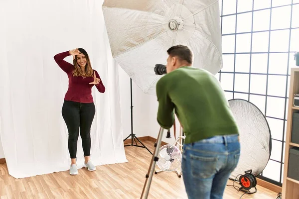 Fotoğraf stüdyosunda gülümseyen genç bir kadın, mutlu yüzlü eller ve parmaklarla çerçeve yapıyor. yaratıcılık ve fotoğrafçılık kavramı. 