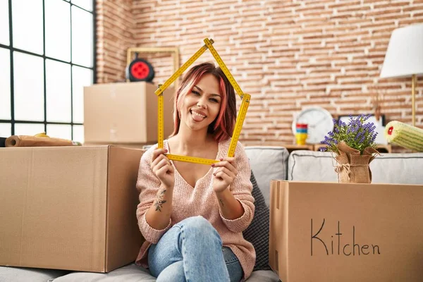 Yeni evdeki kanepede oturan beyaz bir kadın komik bir ifadeyle dilini dışarı çıkartıyor.. 