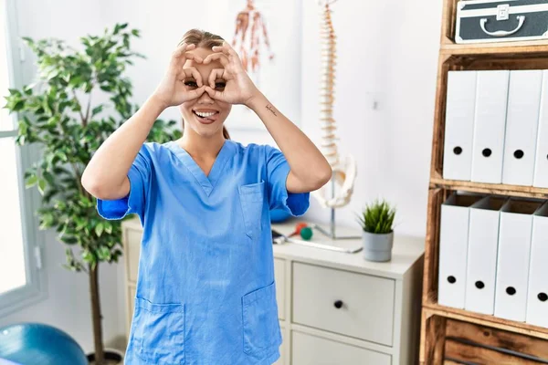 Young Caucasian Woman Working Pain Recovery Clinic Doing Gesture Binoculars — Stock Photo, Image