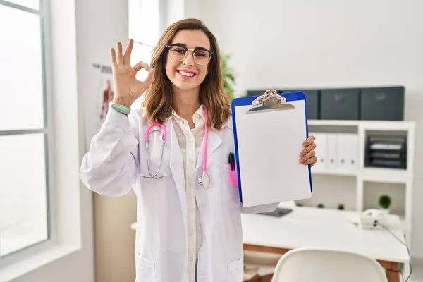 Genç Doktor Kadın Pano Tutuyor Parmaklarıyla Imza Atıyor Gülümsüyor — Stok fotoğraf