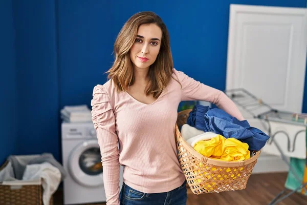 Ung Kvinna Som Håller Tvättkorg Avslappnad Med Allvarliga Ansiktsuttryck Enkel — Stockfoto