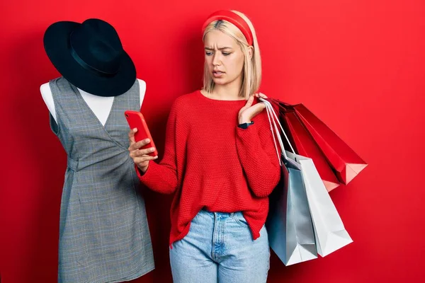 Beautiful Blonde Woman Holding Shopping Bags Smartphone Clueless Confused Expression — 图库照片