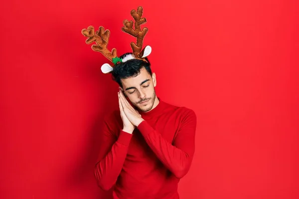 若いですヒスパニック男身に着けていますかわいいクリスマストナカイ角睡眠疲れて夢を見ますと一緒に手でポーズします — ストック写真