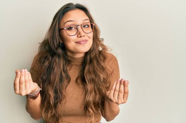 Gündelik kıyafetler ve gözlük takan genç İspanyol kız. Elleriyle para hareketi yapıyor. Maaş ve milyonerlik işi istiyor. 