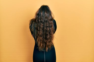 Genç İspanyol kız dalgıç neoprene üniforması giyiyor. Arkaya bakıyor ve kollarını kavuşturuyor. 