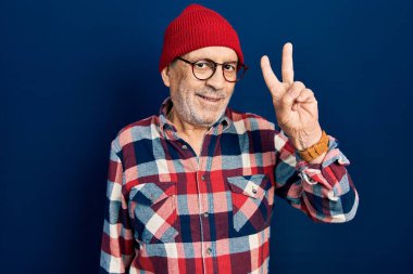 Yakışıklı, hippi giysili, yün şapkalı, iki numaralı parmaklarıyla gösteriş yapan, kendine güvenen ve mutlu bir adam.. 